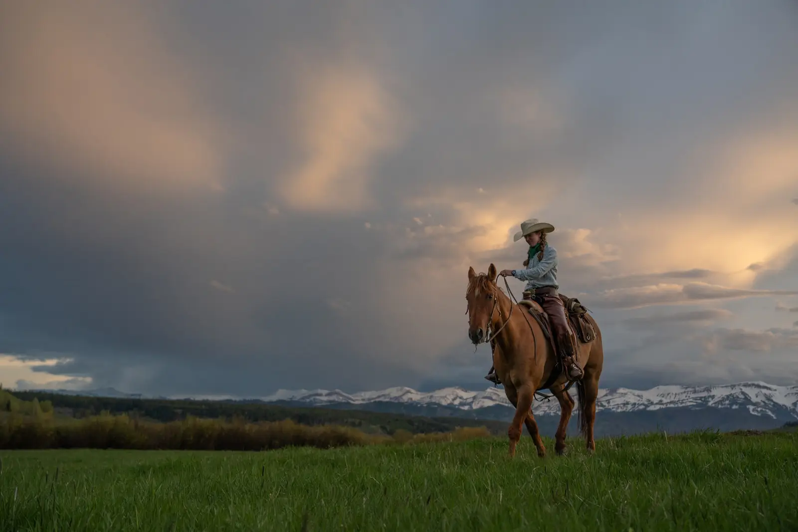 A woman riding on horseback across a field in the Gros Ventre wilderness.